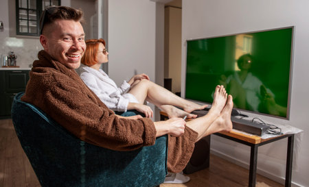 Coronavirus pandemic. Vacation at home. Quarantine. A man and a woman in bathrobes are sitting in...