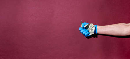 gloved hand squeezes money. Coronavirus pandemic. The concept of the struggle for survival. Place for text.の写真素材