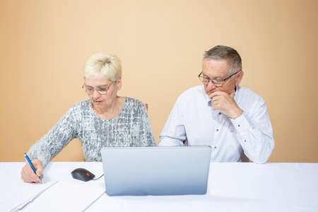 Older education. Learning to work online through a computer. Elderly man and woman are learning how to work with a laptop.の写真素材