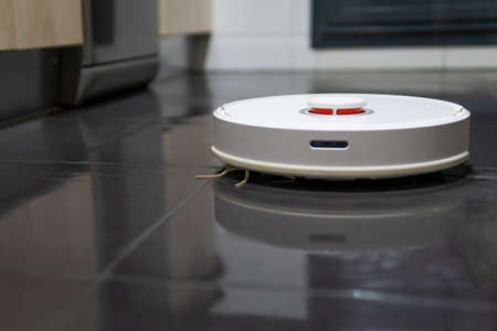 robot vacuum cleaner cleaning the kitchen floorの写真素材
