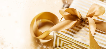 Magical arrangement of packed present decorated with gold ribbon shining in light.