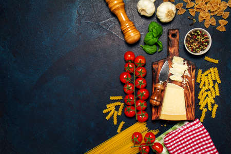 Italian food or ingredients background with fresh vegetables, pasta, cheese parmesan and spices. Top view, view from above. Copy space. Dark background.の写真素材