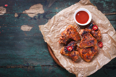 Roasted barbecue chicken wings with bbq sauce, italian herbs, olive oil and pepper, top view with copy spaceの写真素材