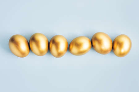 Golden eggs on pastel background. Flat lay. Easter or financial concept.の写真素材
