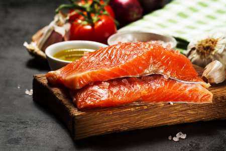 Tasty colorful Food Background with fresh Raw Fish Salmon and Cooking Ingredients - Olive Oil, Salt, Tomatoes and Spices on Old Metal Tray. Cooking, Healthy Food Concept.の写真素材