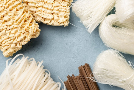 Various types of dry noodle on blue background. Top view.