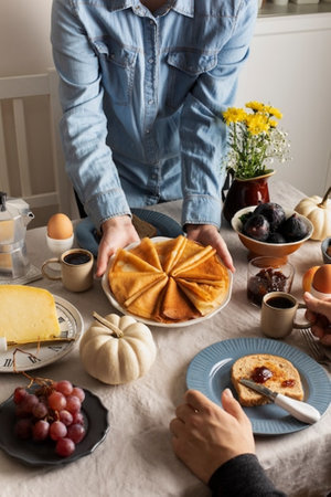 cropped view of woman holding plate with pancakes on table in kitchenの写真素材