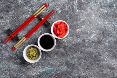 Soy sauce, wasabi, ginger and chopsticks on stone background