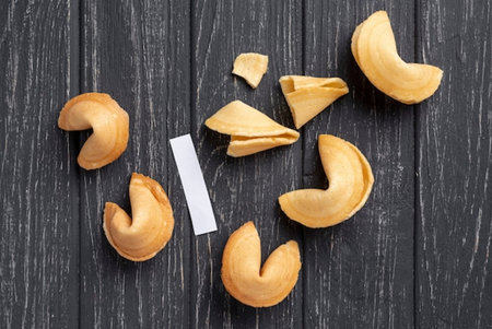 Fortune cookies with blank card on black wooden background. Top view