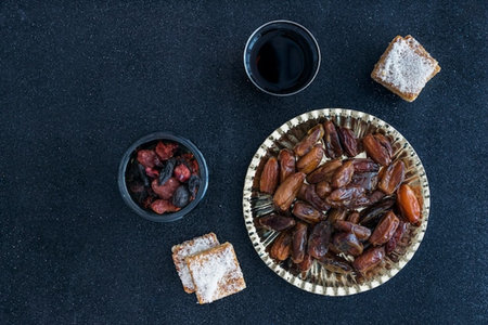 Top view of dried date fruits in a bowl and glass of red wine on black backgroundの写真素材