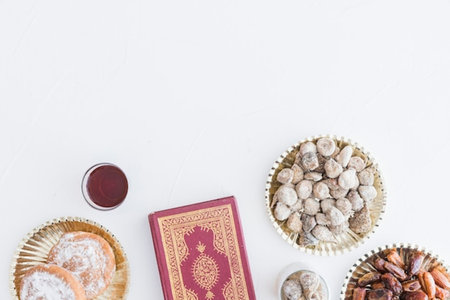 Ramadan Kareem background with dates, sweets and Quran on white tableの写真素材
