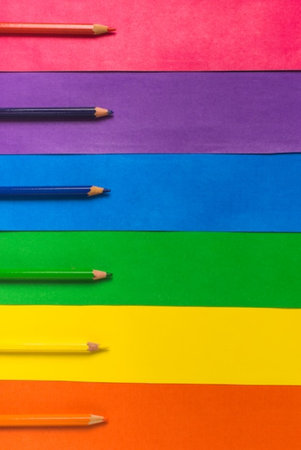 Colored pencils in a row on multicolored paper backgroundの写真素材