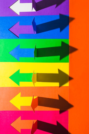 Paper arrows in different directions on a multicolored background. Conceptual image.の写真素材