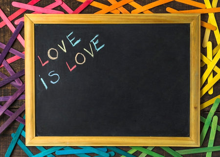 Love is love written on a blackboard with colorful wooden sticks aroundの写真素材