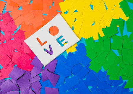 Love message on a white sticker on a multicolored paper backgroundの写真素材