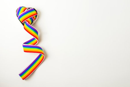 Rainbow ribbon in the shape of a heart on a white backgroundの写真素材