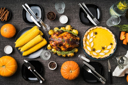 Thanksgiving dinner with roasted turkey, pumpkins, olives, and corn on wooden backgroundの写真素材