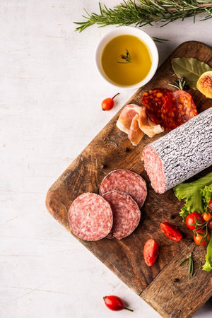 Sliced salami sausage on wooden cutting board, top view