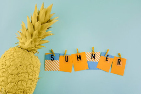 summer background with yellow pineapple and blue striped clothespins on blue backgroundの写真素材
