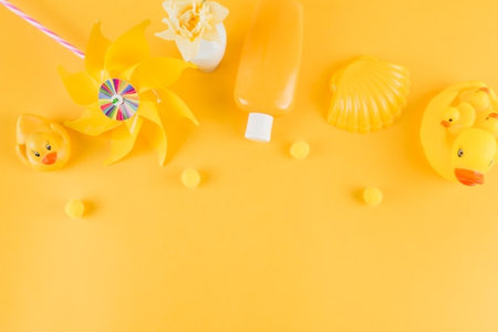 Baby cosmetics and toys on yellow background. Flat lay, top view.の写真素材