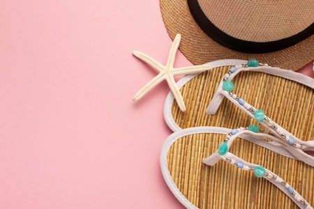 Top view of flip flops, straw hat and starfish on pink backgroundの写真素材