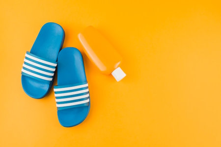 Flip flops and sunscreen on a yellow background. Top viewの写真素材