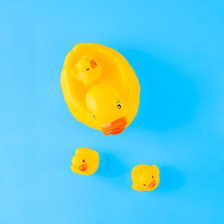 Yellow rubber ducklings on blue background. Flat lay, top view.