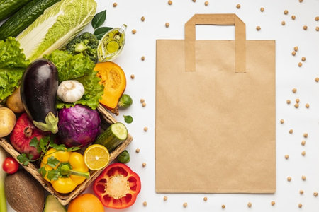 top view of paper bag with fresh vegetables and fruits on white backgroundの写真素材