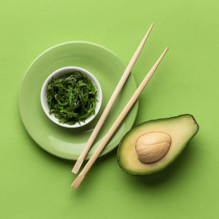Green salad with avocado and chopsticks on green background, top viewの写真素材