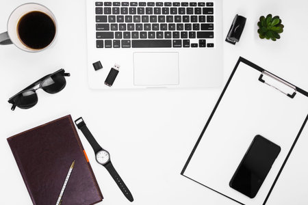 White office desk table with laptop, smartphone, supplies and coffee cup. Flat lay, top view