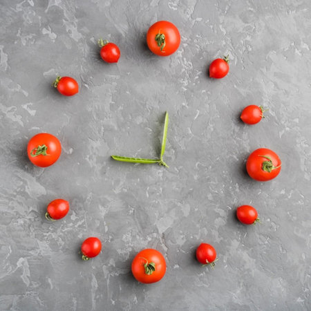 Clock made of fresh tomatoes on grey background, flat lay. Time management conceptの写真素材