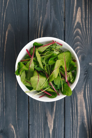 Bowl of fresh green salad leaves on wooden background, top viewの写真素材