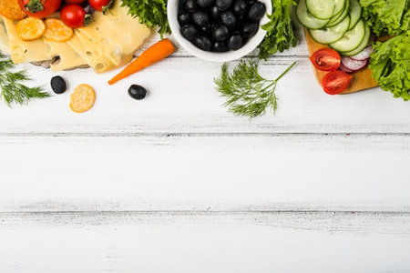 Fresh vegetables, cheese and olives on wooden background. Top view with copy spaceの写真素材