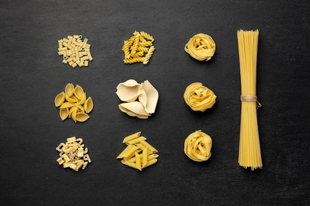 Different types of pasta on a dark background. Top view, flat layの写真素材