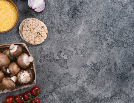 Ingredients for cooking risotto: porcini mushrooms, tomatoes, corn, onion on stone background. Top view with copy spaceの写真素材