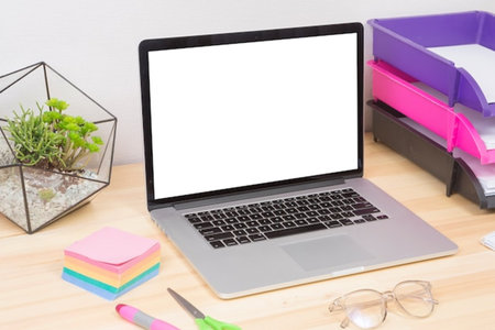 Laptop computer with blank screen and office supplies on wooden desk.