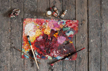 Palette, tubes of oil paint and artist paint brushes on a wooden backgroundの写真素材