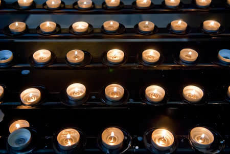 Small candles burning on shelves in catholic churchの写真素材