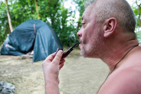 Sumy, Ukraine - Jule 6, 2017: Senior man smoking a pipe admiring the beauty of natureのeditorial素材