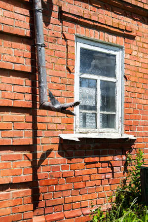 Vintage red brick wall with drain pipe and white windowの写真素材