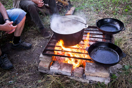 Cooking dinner in iron kettle at bonfire. Bonfire cooking. Selective focus, blurの写真素材