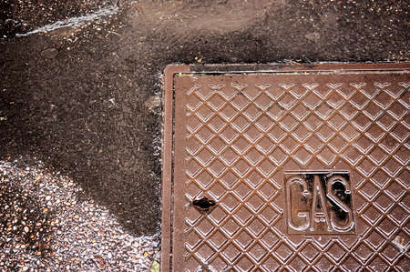 Metal brown rusty manhole cover on a pedestrian walkwayの写真素材