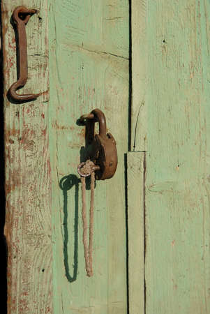 Old rusty metal iron padlock with key on a wood doorの写真素材