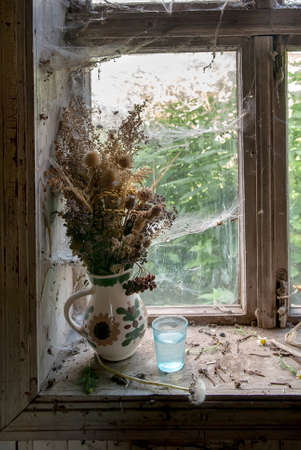 Window with cobwebs and bouquet of dried flowers. Selective focusの写真素材