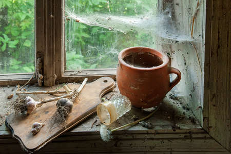 Jug on the windowsill with cobweb of rustic window. Selective focusの写真素材