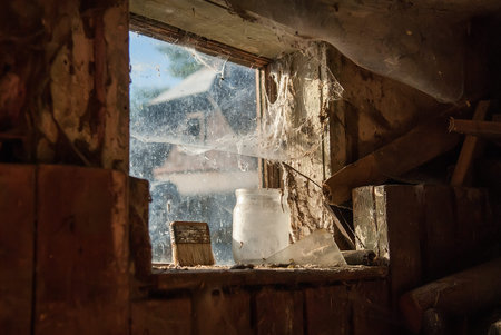 Interior view of a barn, window covered in dusty cobwebs. Selective focus