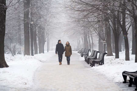 Kyiv, Ukraine - January 17, 2017: Couple enjoying a winter stroll and walking on the snowy alley of the Mariinsky Park. It is one of the most visited amusement parks in Kyiv. Selective focusのeditorial素材