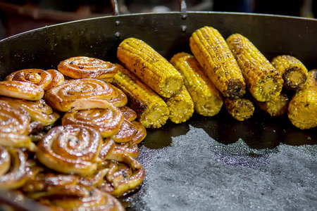 Grilled corns, sausages sold on Christmas market. Winter holidays outdoors. Selective focus
