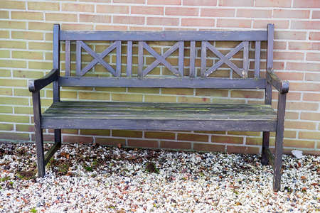 Old wooden bench and colorful pebbles against a brick wallの写真素材