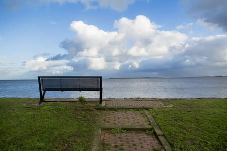 Wooden bench on open space overlooking a beautiful sea viewの写真素材